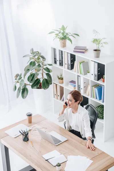 Fröhliche Geschäftsfrau Spricht Modernen Büro Mit Laptop Auf Dem Smartphone — Stockfoto