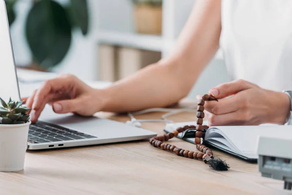 Cropped View Businesswoman Using Laptop Holding Rosary Beads Workplace — Stock Photo, Image