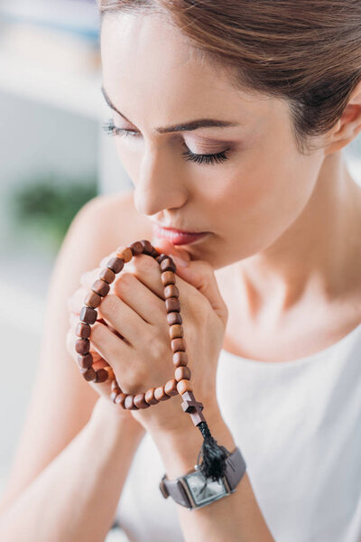 beautiful woman praying with wooden rosary beads