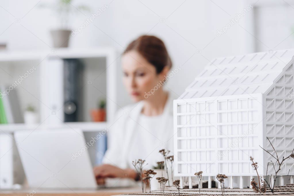 selective focus of house model and architect working with laptop in office