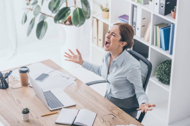high angle view of stressed businesswoman screaming at workplace