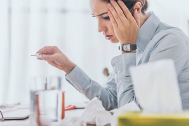 İşyerinde oturan ve elektrik termometre tutan hasta işkadını