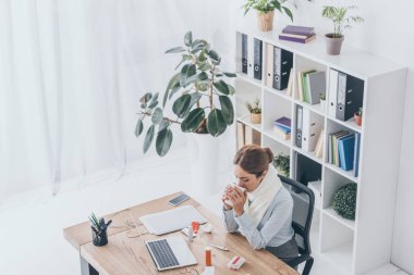 ofiste oturan ve sıcak çay içme fularlı hasta işkadını yüksek açılı görünüş