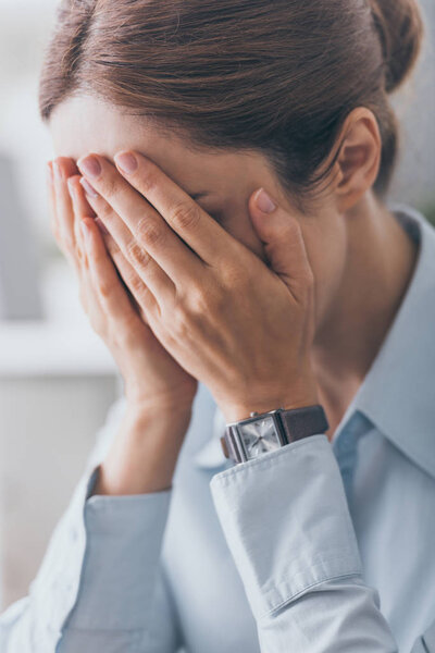 крупным планом стрессовая взрослая деловая женщина, прикрывающая лицо руками
