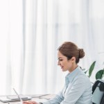 Side view of smiling beautiful businesswoman working with tablet at office
