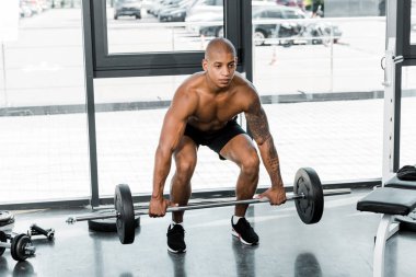 Kas gömleksiz genç Afro-Amerikan sporcu spor salonunda halter kaldırma