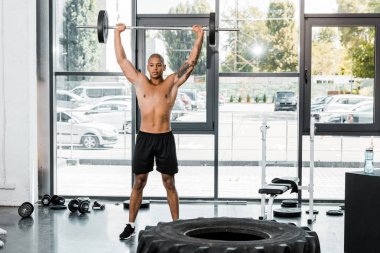 kaslı çıplak göğüslü Afrikalı-Amerikalı sporcu spor salonunda halter kaldırma 