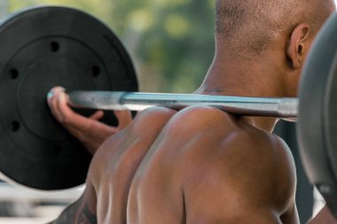 cropped shot of muscular african american sportsman lifting barbell in gym clipart