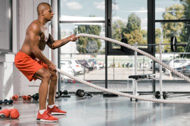 Afro-Amerikan atlet spor salonunda savaş halatlar ile çalışma dışarı yan görünüm