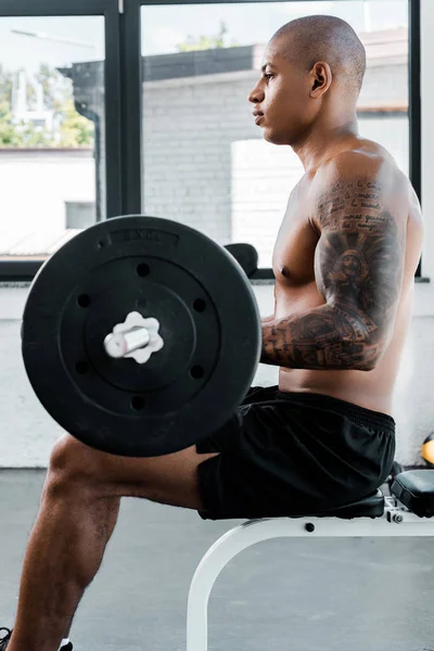 Visão Lateral Desportista Tatuado Muscular Sentado Banco Segurando Barbell Ginásio — Fotografia de Stock