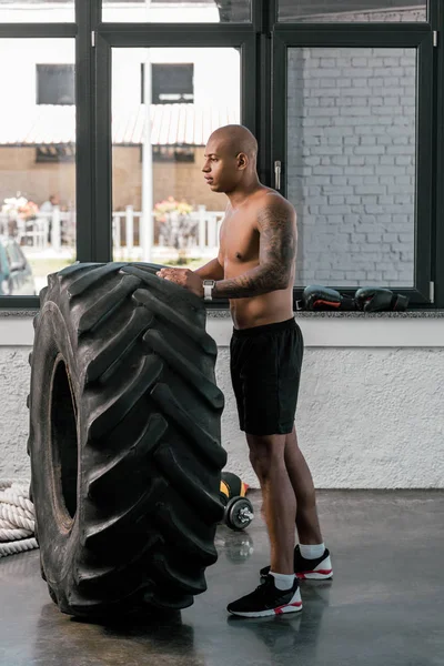 Vista Lateral Joven Musculoso Entrenando Con Neumático Mirando Hacia Otro — Foto de stock gratuita