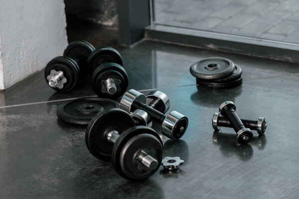 selective focus of iron dumbbells on floor at gym