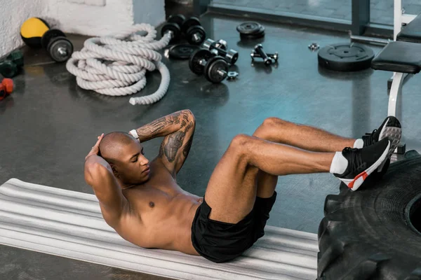 Τατουάζ Αφροαμερικάνος Αθλητής Κάνει Abs Πόδια Στο Ελαστικό Στο Γυμναστήριο — Φωτογραφία Αρχείου