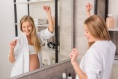 glücklich schöne schwangere Frau im Bademantel tanzt vor Spiegel im Badezimmer