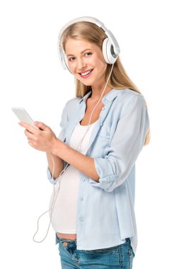 gülümseyen hamile kadın üzerinde beyaz izole akıllı telefon ve kulaklık ile müzik dinleme