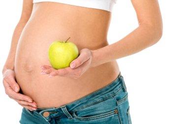 hamile kadının göbek ve üzerinde beyaz izole holding yeşil elma dokunmadan kırpılmış görünümü