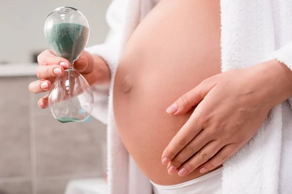 Tiro Recortado Mujer Embarazada Sosteniendo Reloj Arena Cerca Barriga Baño — Foto de stock gratis