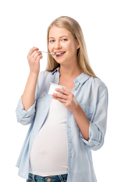 smiling pregnant woman eating yogurt with spoon isolated on white