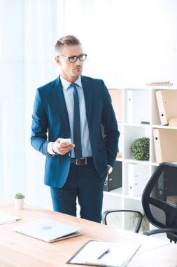 akıllı telefon tutarak ve uzak ofis seyir gözlük'kendine güvenen iş adamıdır