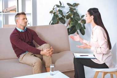man and female psychologist talking during therapy session