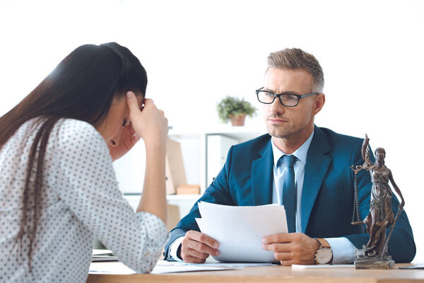 юрист держит документы и работает с расстроенным клиентом
  