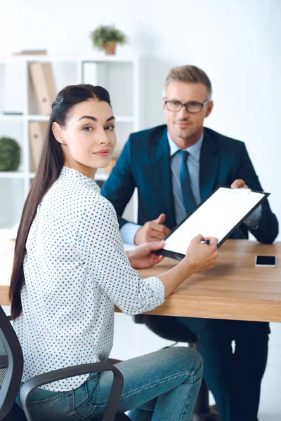 Abogado Sosteniendo Portapapeles Mientras Cliente Femenino Firma Contrato Sonriendo Cámara — Foto de Stock