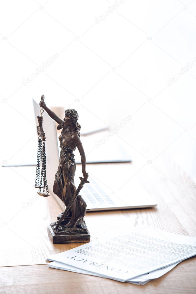 lady justice statue, contract and laptop computer on table