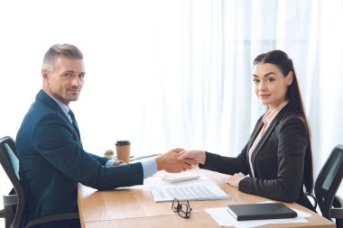 business partners shaking hands at workplace in office clipart