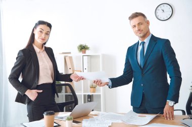 businesswoman giving document to colleague at workplace in office clipart