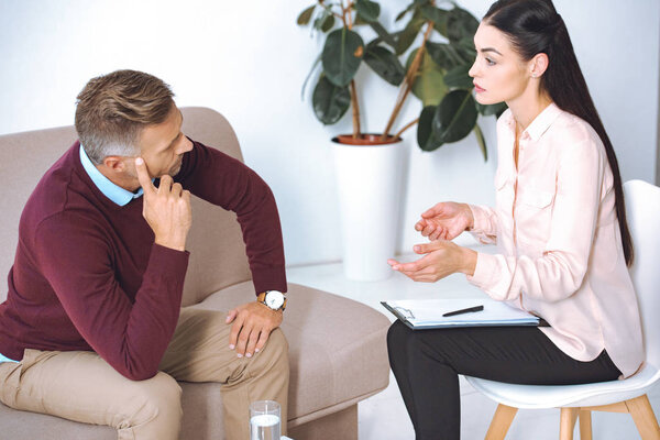 female psychologist talking on patient on sofa during therapy session