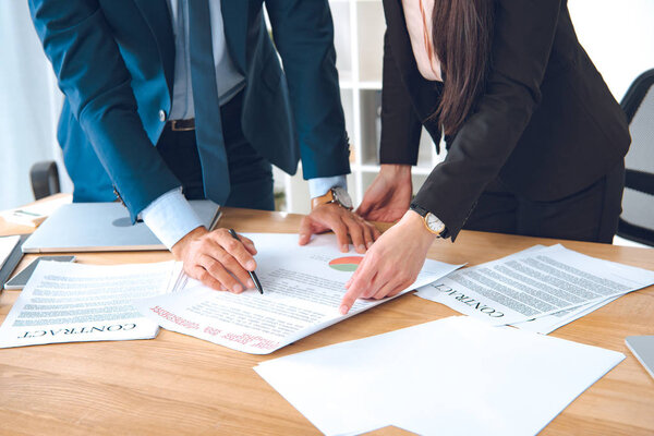 cropped shot of businesspeople with documents at workplace in office