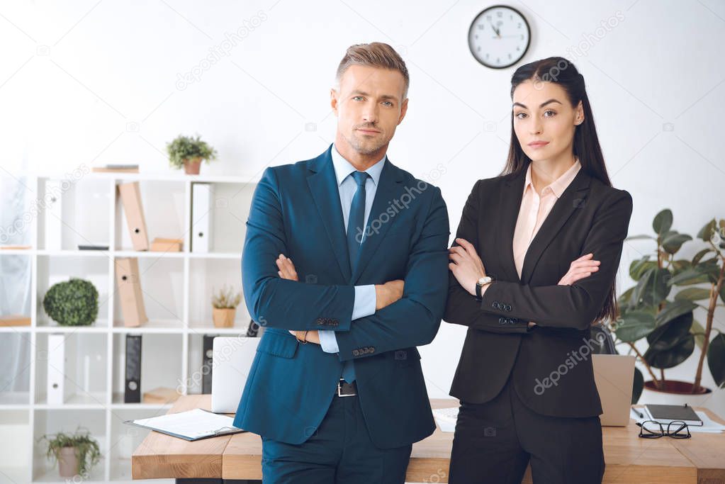 portrait of businesspeople with arms crossed standing at workplace in office