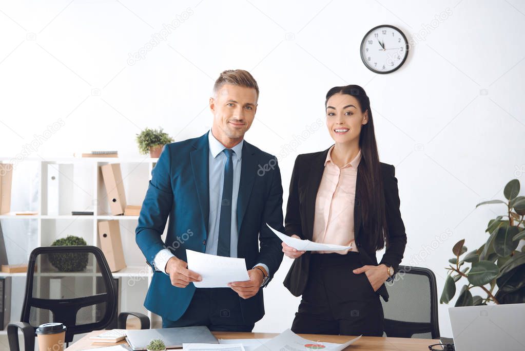 portrait of smiling business colleagues with papers at workplace in office