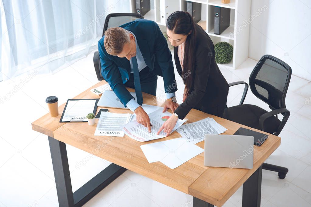 high angle view of business colleagues doing paperwork at workplace in office