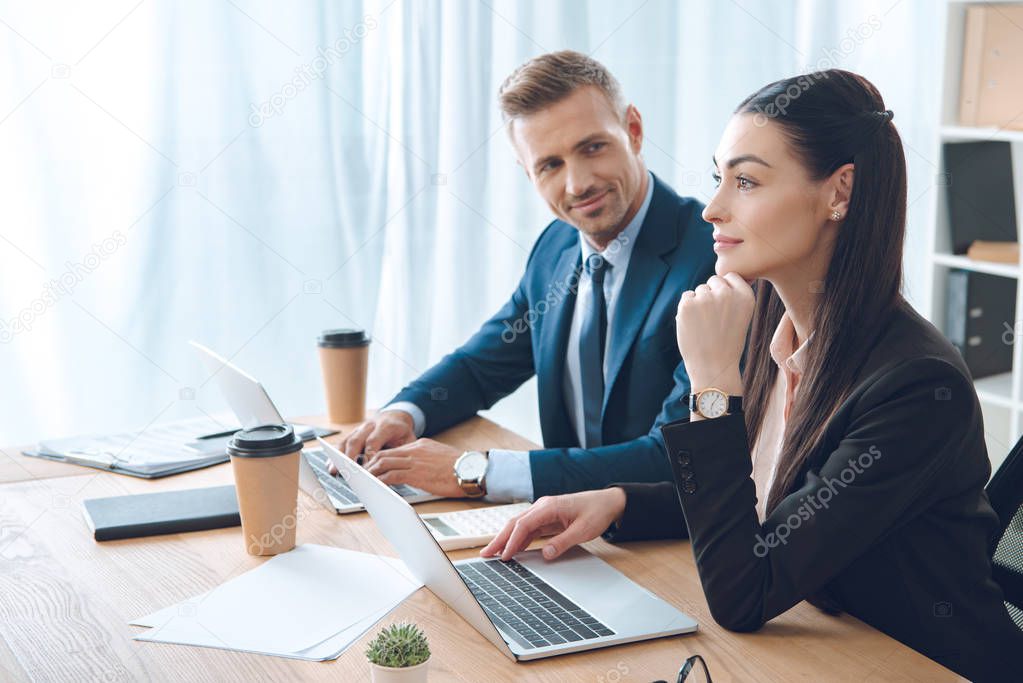 side view of businesspeople working at workplace with laptop in office