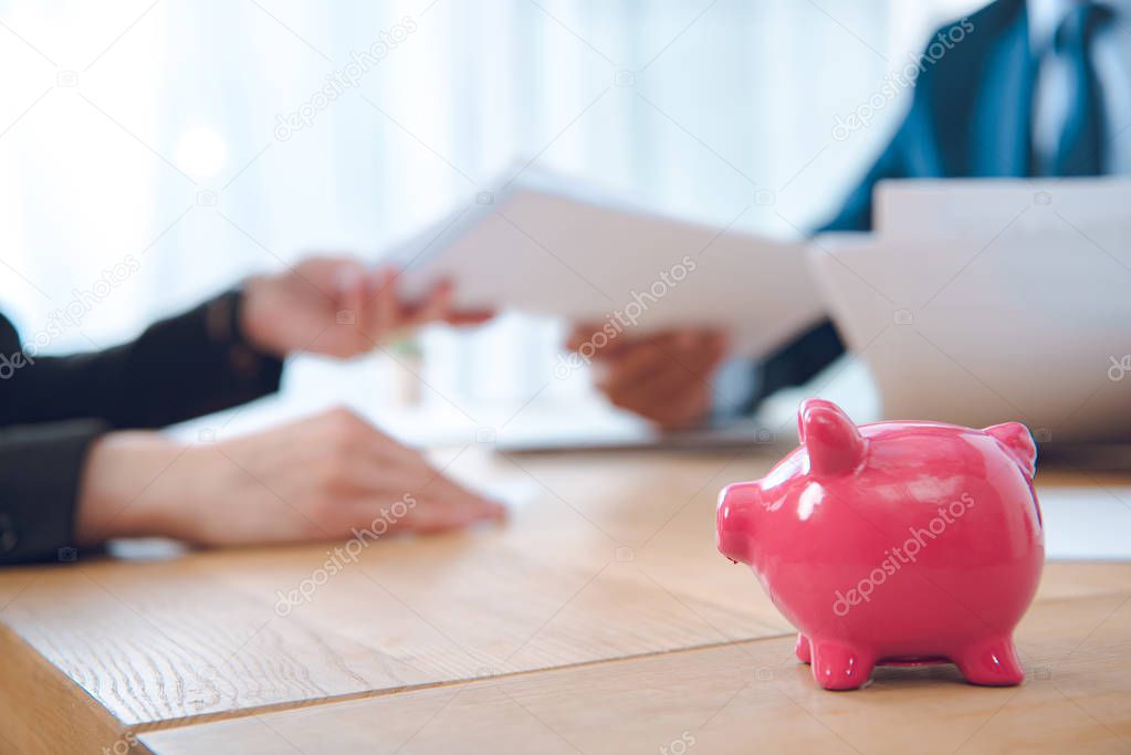 partial view of businessman giving documents to colleague at workplace in office