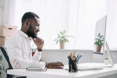 neşeli yakışıklı Afrikalı-Amerikalı işadamı bilgisayarda Office çalışan yan görünüm