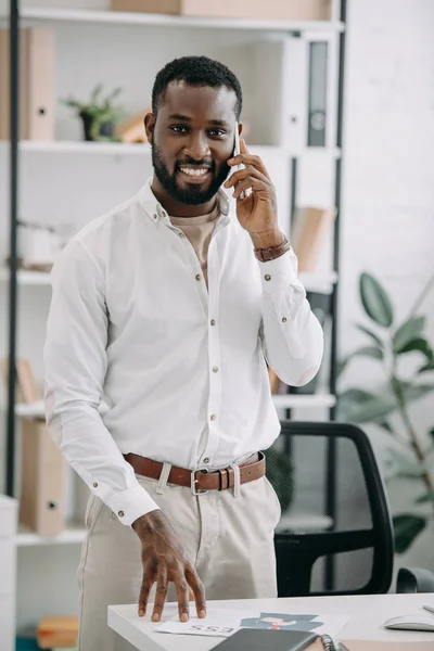 Handsome African American Businessman Standing Table Talking Smartphone Office — Free Stock Photo