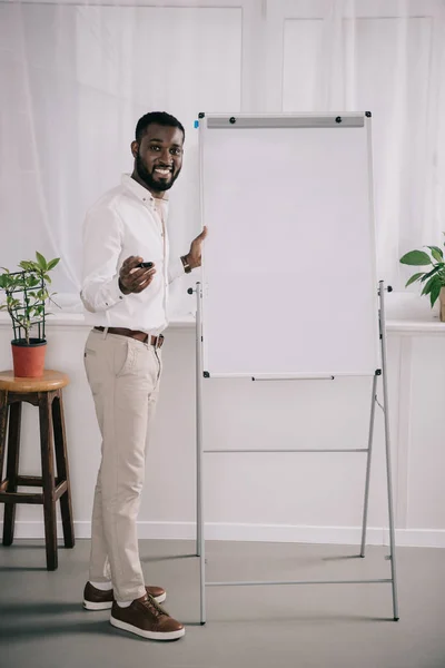 Usmívající Pohledný Americký Podnikatel Stojící Poblíž Flipchart Ukázal Úřadu — Stock fotografie