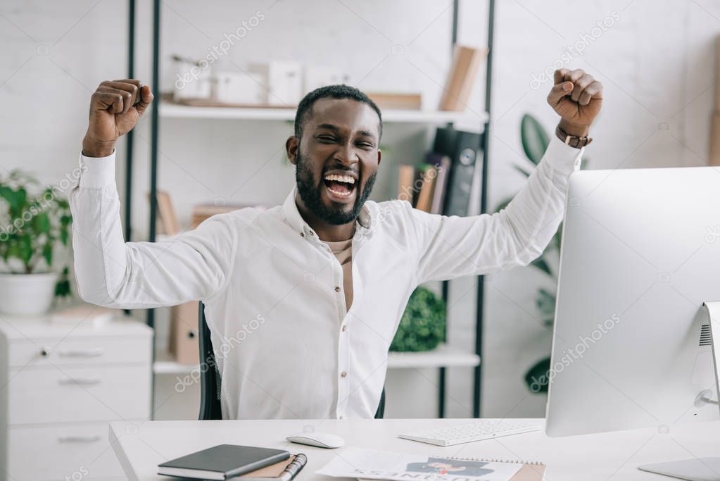 Excited african american businessman screaming and showing yes gesture in office. Man celebrate win a bet with a gambling, soccer bet, sports gambling