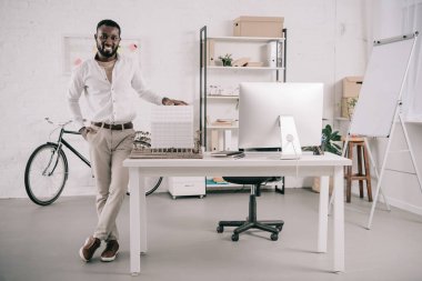 neşeli yakışıklı Afrikalı-Amerikalı mimar mimari modeli dokunmaktan ve Office kamera bakıyor