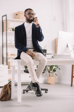 modern ofis masada otururken Smartphone konuşurken yakışıklı başarılı Afrikalı-Amerikalı iş adamı  