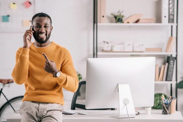 Smiling Handsome African American Designer Orange Sweater Talking Smartphone Pointing — Stock Photo, Image