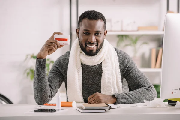 Smiling Diseased African American Businessman Holding Pill Box While Sitting — Stock Photo, Image