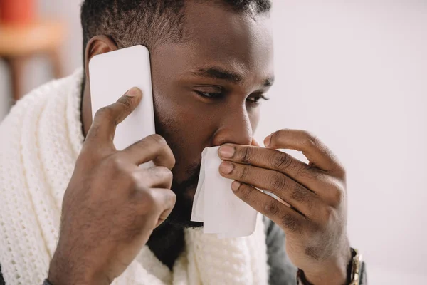 鼻水ナプキンを押しながらスマート フォンで話していると病気のアフリカ系アメリカ人 — ストック写真