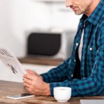 Plan recadré de l'homme en chemise à carreaux lecture journal de voyage à la maison