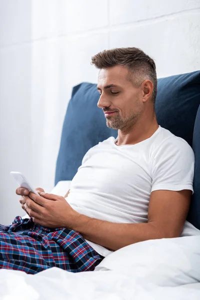 Hombre Camiseta Blanca Usando Teléfono Inteligente Durante Mañana Cama Casa — Foto de stock gratis