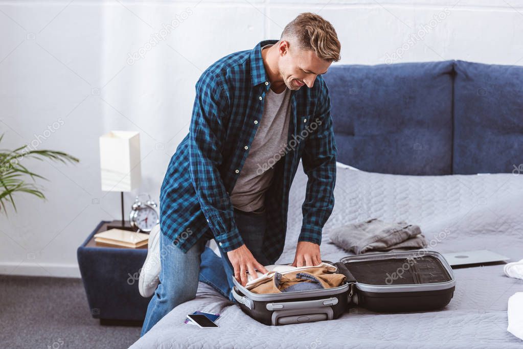 adult male traveler packing luggage in bedroom at home 