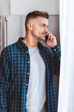 smartphone ile konuşmak ve penceresine bakarak kareli gömlekli adam sigara 
