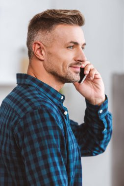 smartphone ile konuşmak ve uzak evde seyir yakışıklı gülümseyen adam yan görünüm